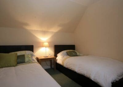 Upstairs bedroom with double and single beds and simple white covers